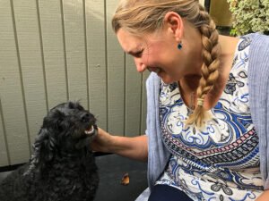 Lesley Huntley - Professional dog sitter in Christchurch petting a spoodle during a home visit